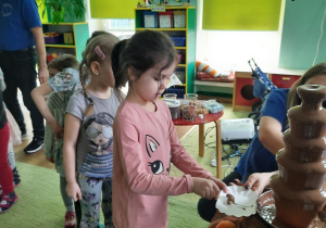 dzieci stoj ąw kolejce do fontanny z czekoladą