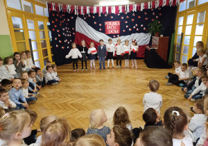 dzieci ubrane na galowo śpiewają piosenkę