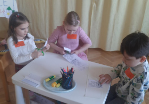 dzieci rozwiązują zadania siedząc przy stoliku