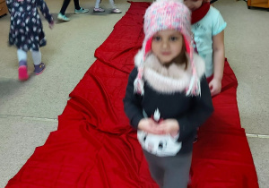 dziewczynka prezentuje zimowe akcesoria na "czewonym dywanie"