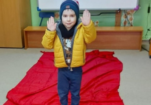 chłopiec prezentuje zimowy strój na "czewonym dywanie"