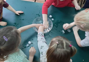 dzieci wyławiają kostki lodu z miski z wodą