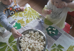 dzieci naklejają popcorn na zielony karton