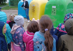 Dzieci oglądają pojemniki do segrgowania śmieci ustawione niedaleko przedszkola