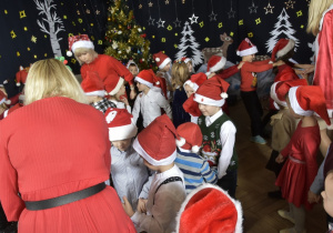 dzieci tańczą w czapkach Mikołajów