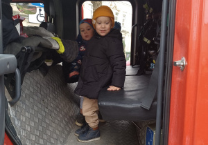 Chłopiec siedzi w wozie strażackim