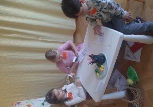 dzieci rozwiązują zadania siedząc przy stoliku