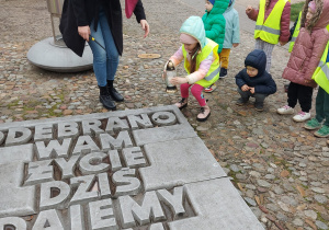 dziewczynka stawia znicz na płycie pomnika