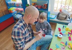 tata z dziewczynką sklejają ozdobę świąteczną