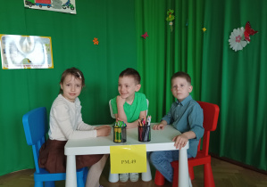dziewczynka i chłopcy siedzą przy stoliku