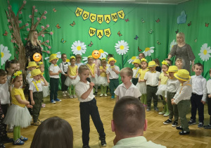 dwóch chłopców recytuje wiersz na tle innych dzieci i wiosennej dekoracji