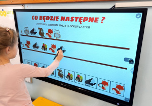 Dziecko uzupełnia sekwencję obrazków zwierząt na ekranie dotykowym w zadaniu „Co będzie następne?”.