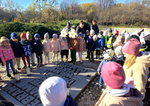 Dzieci z opiekunami zapalają znicze przy Pomniku Pękniętego Serca