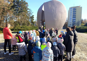 Dzieci z opiekunami zapalają znicze przy Pomniku Pękniętego Serca