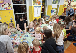 dzieci i rodzice wykonują ozdoby świateczne