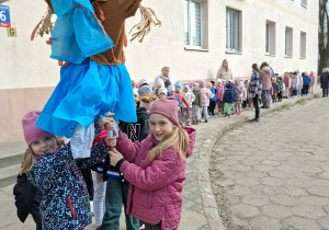 dzieci ida na spacer trzymając Marzannę