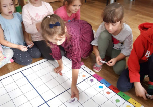 grupa dzieci układa na planszy obrazki wg instrukcji