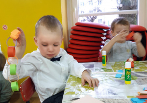chłopiec skleja łańcuch z kolorowych pasków papieru