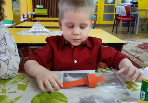 chłopiec skleja łańcuch z kolorowych pasków papieru